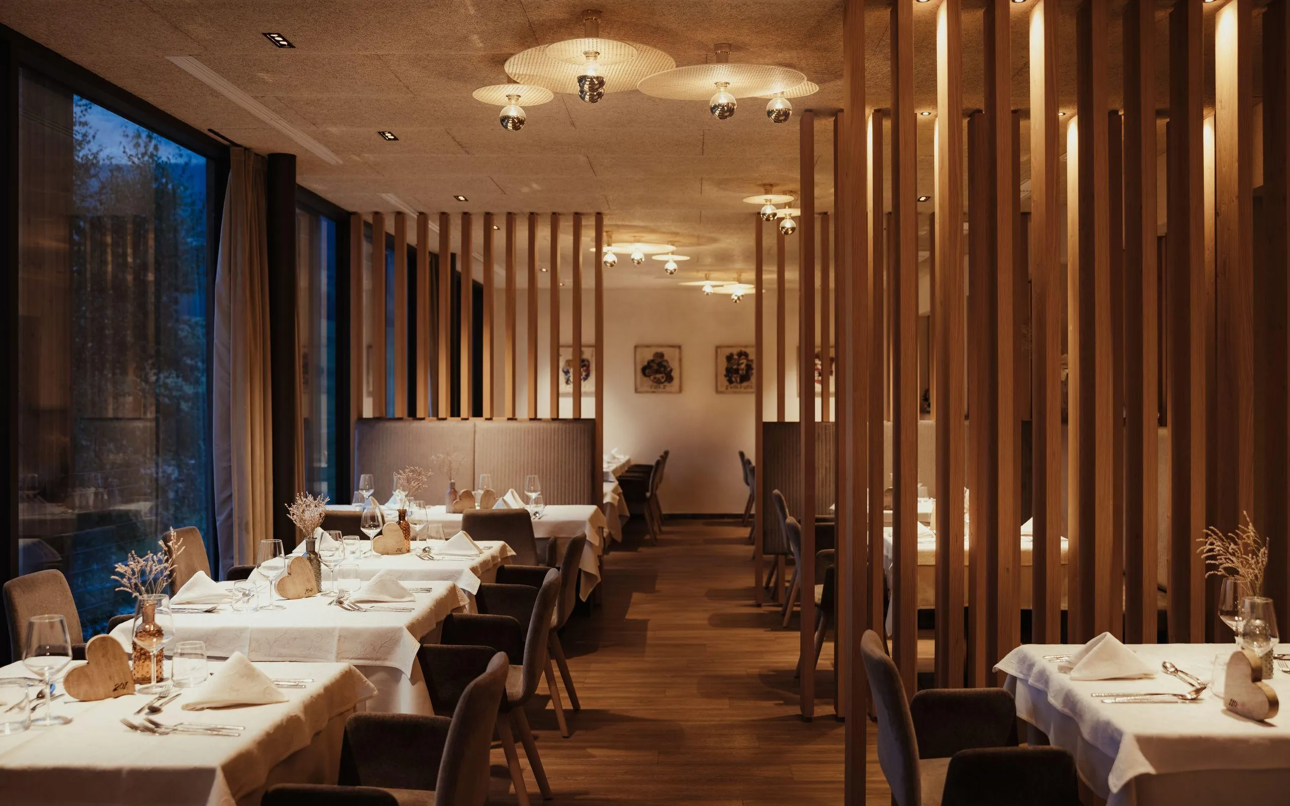 L'elegante sala da pranzo dell'Hotel Lech da Sompunt, caratterizzata da elementi in legno, luci soffuse e tavoli apparecchiati con cura, crea un'atmosfera calda e invitante.