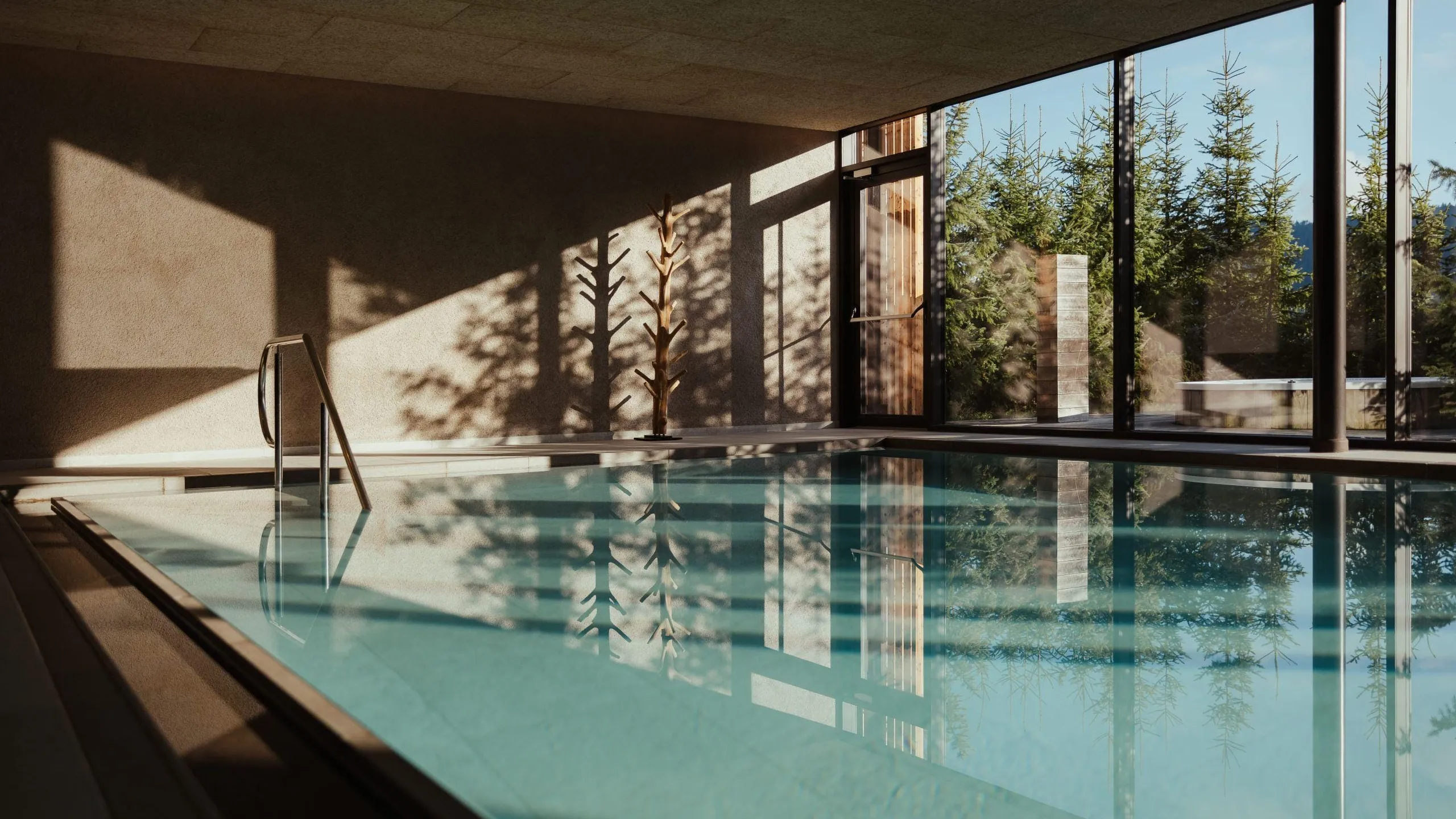 Indoor pool at Hotel Lech da Sompunt in La Villa, Alta Badia, with large windows allowing natural light and views of surrounding greenery.