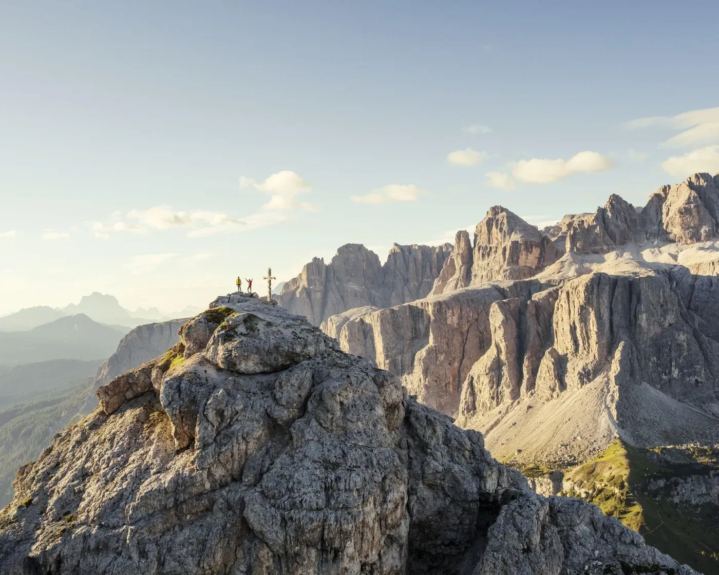 Tre escursionisti si ergono trionfanti in cima a una cima rocciosa del Cir in Alta Badia, con vista sul Gruppo del Sella.