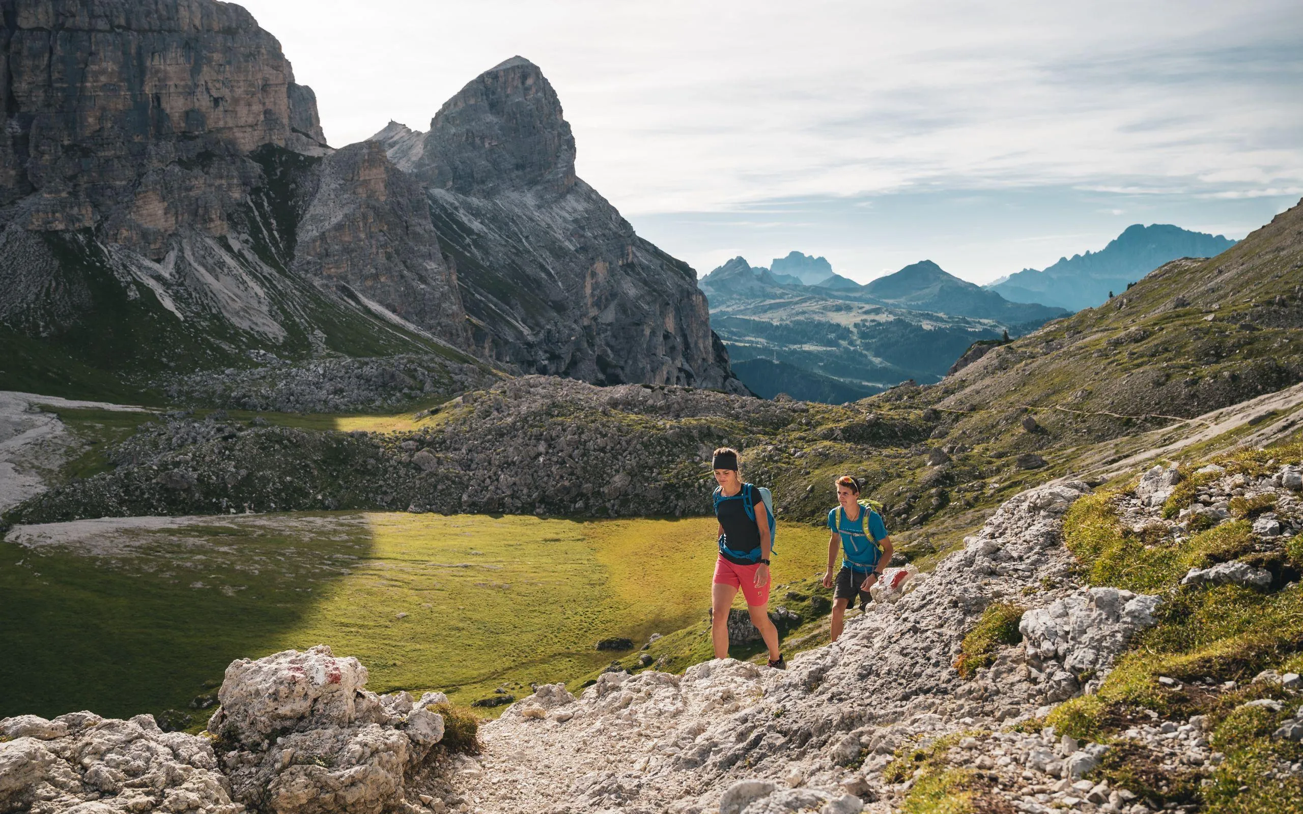 Due escursionisti salgono un sentiero roccioso nel parco naturale Puez-Odle, circondati dalle Dolomiti.
