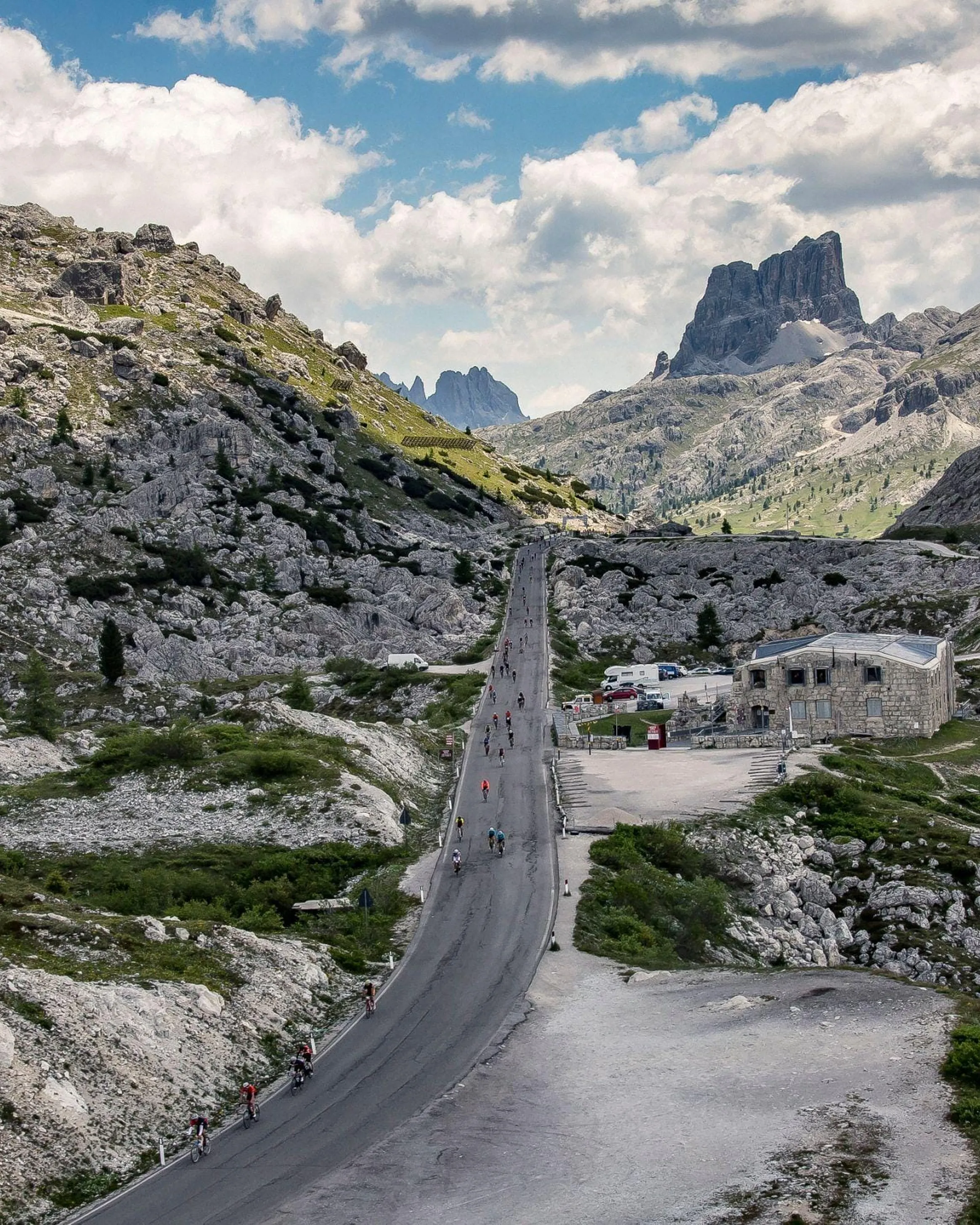 La strada tortuosa del Passo Valparola attraverso un terreno roccioso, con ciclisti in sella, durante la Maratona dles Dolomites.