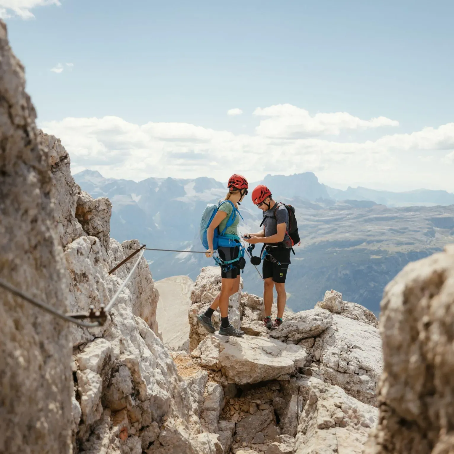 Due scalatori con il casco esaminano l'attrezzatura sulla cima rocciosa del Piz dales Diesc/Cima Dieci in Alta Badia.