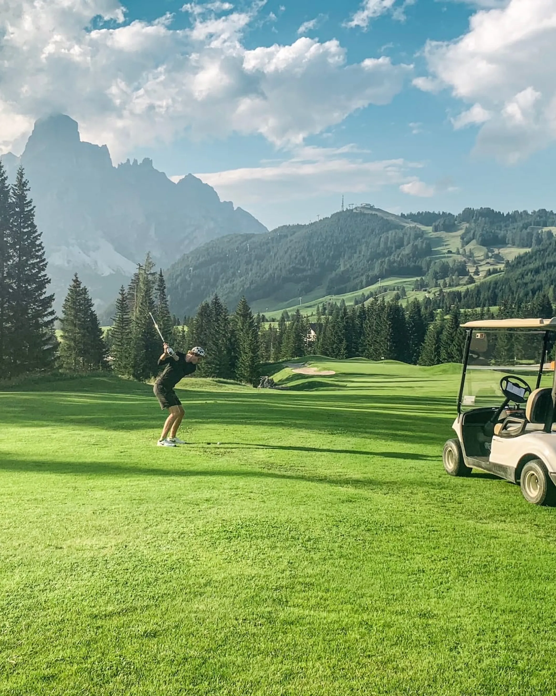 Un golfista si prepara al tee off su un fairway verdeggiante a Corvara – Dolomiti.