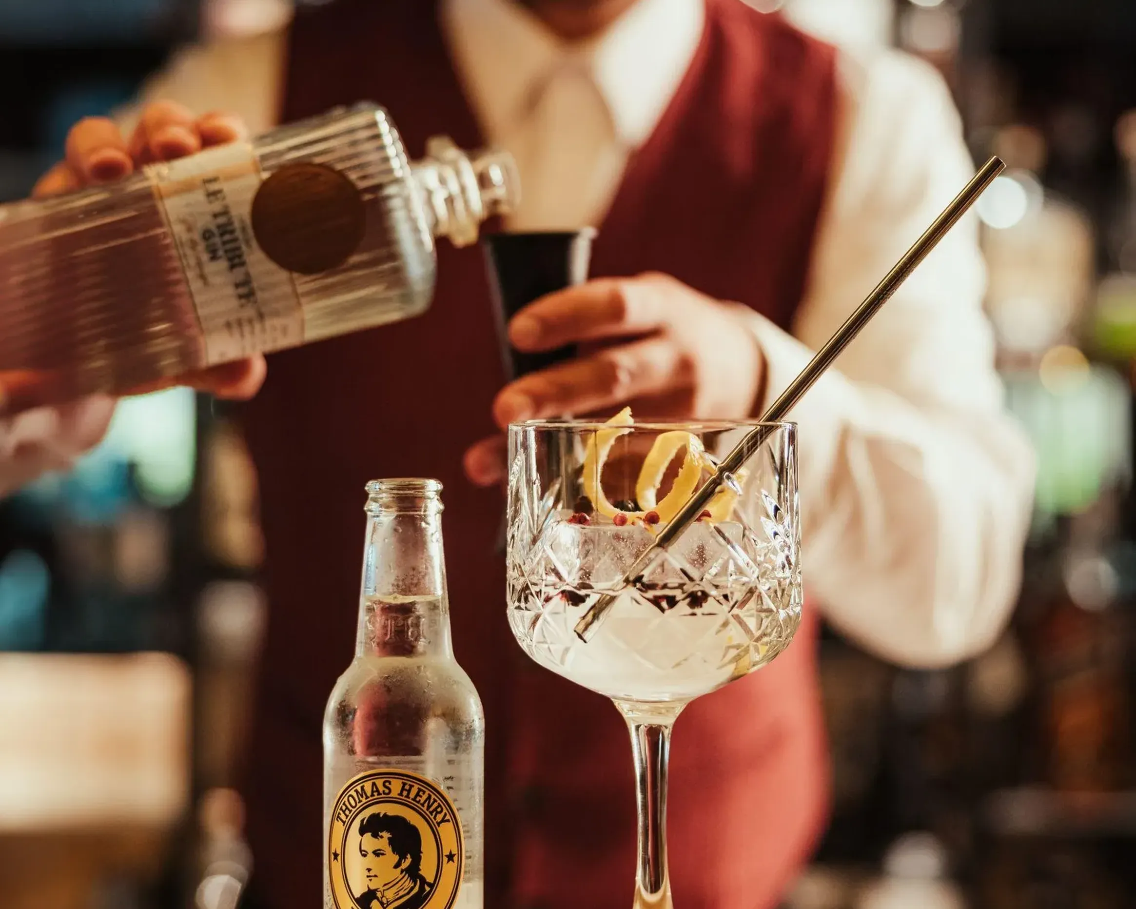 A bartender skillfully pours a gin tonic into a crystal glass adorned with lemon slices at Hotel Lech da Sompunt, Alta Badia.