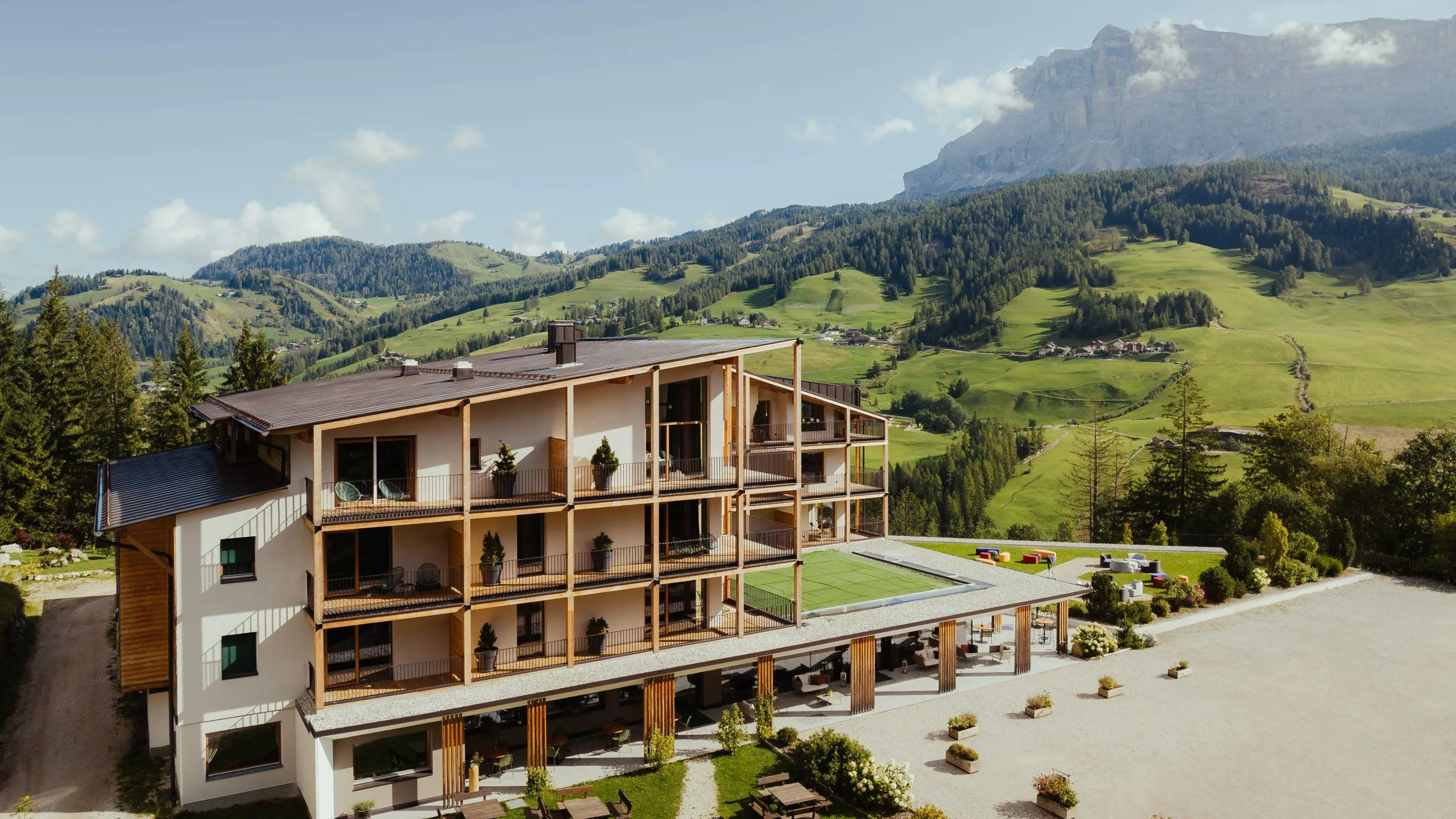 Hotel Lech da Sompunt in La Villa, Alta Badia, showcases modern architecture against lush green meadows of Alta Badia.